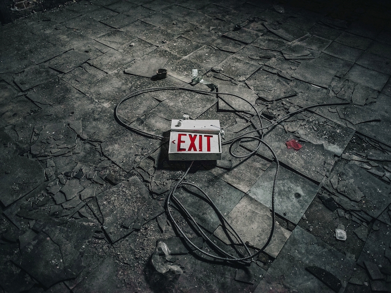 Abandoned building with exit sign on the floor. Original public domain image from Wikimedia Commons